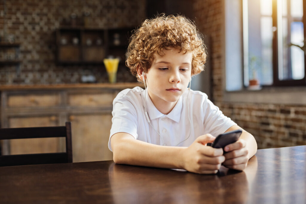 Boy looking concerned while on his phone - for signs of roblox abuse - File Abuse Lawsuit
