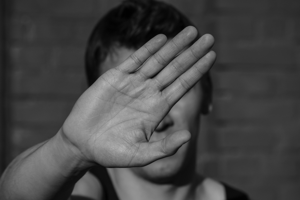 a young man covers his face with hand