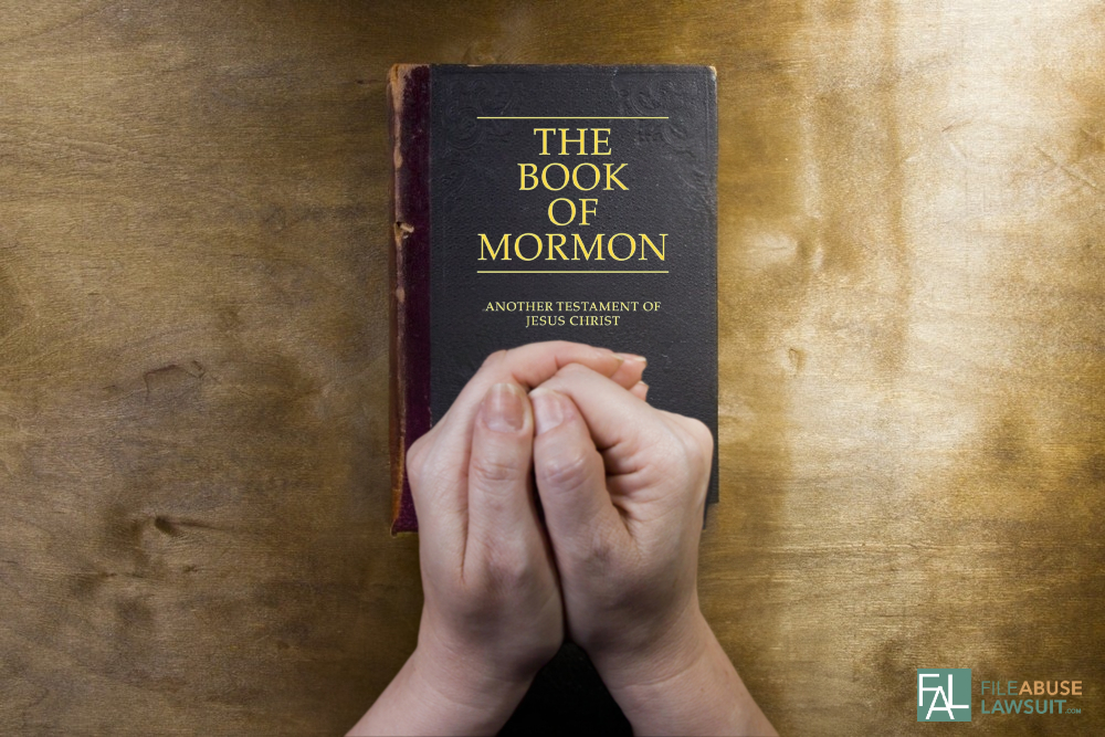 hands resting on the book of mormon - File Abuse Lawsuit