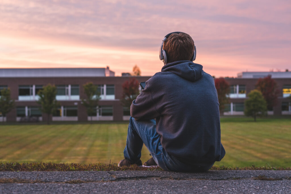 teen boy sitting on high school bleachers showing signs of depression and isolation - School Sexual Abuse Lawyer